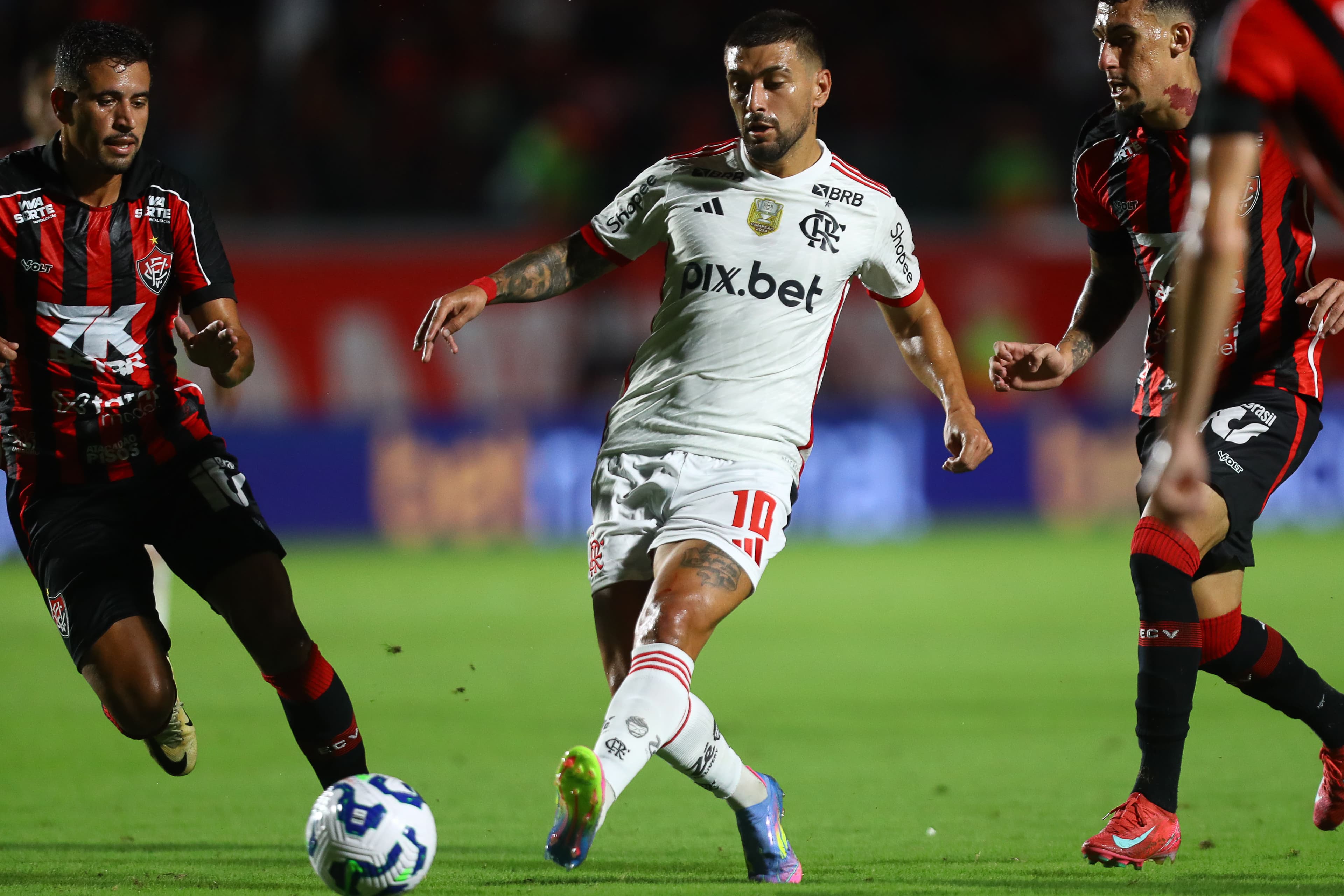 Arrascaeta tenta passe enquanto é observado por dois jogadores do Vitória em jogo contra o Flamengo, no Barradão