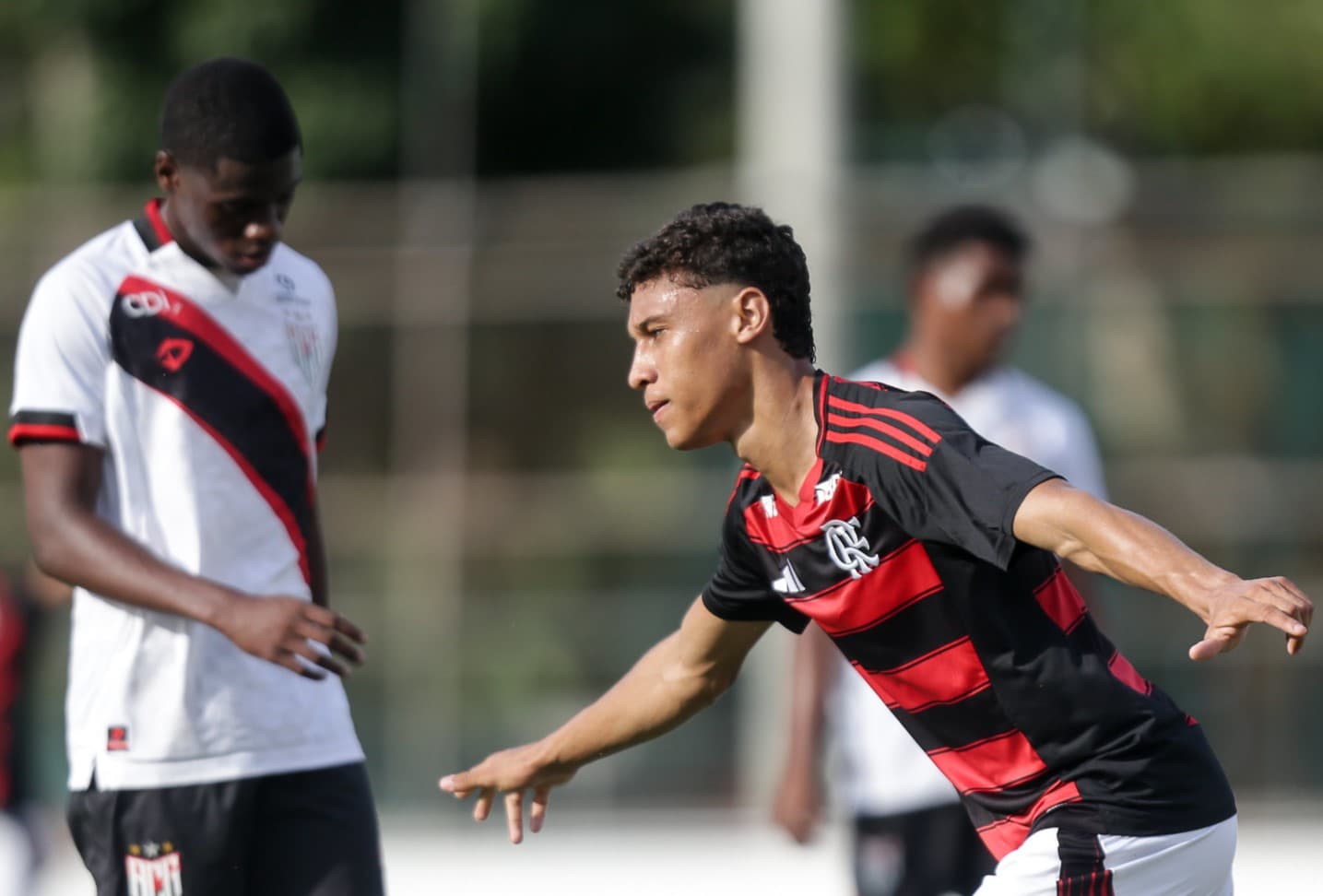 Atleta sub-17 do Flamengo comemora gol, enquanto zagueiro do Atlético-GO lamenta ao fundo