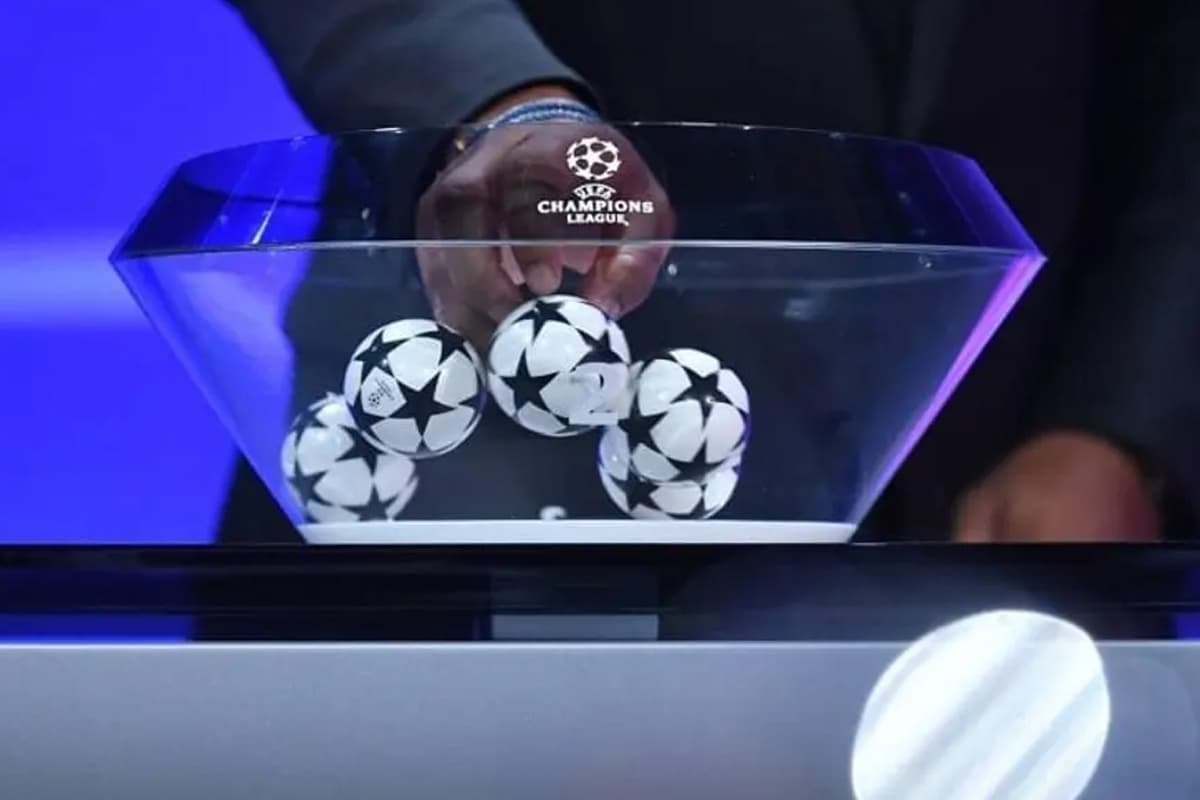 Foto registrada de uma mão escolhendo uma bola de algum time no sorteio da Champions League