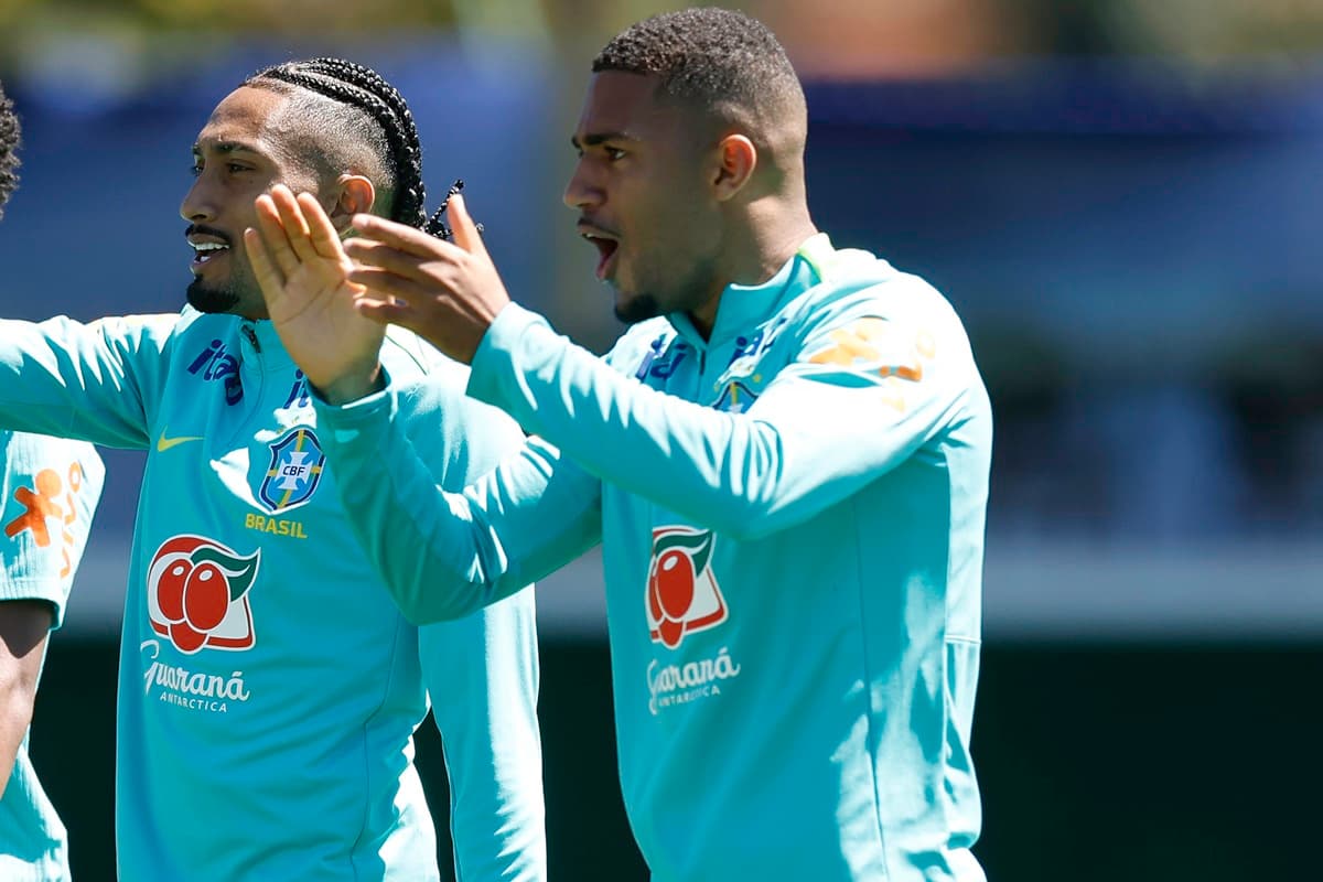 Samuel Lino brinca com demais companheiros fazendo sinal com as mãos em treino da Seleção