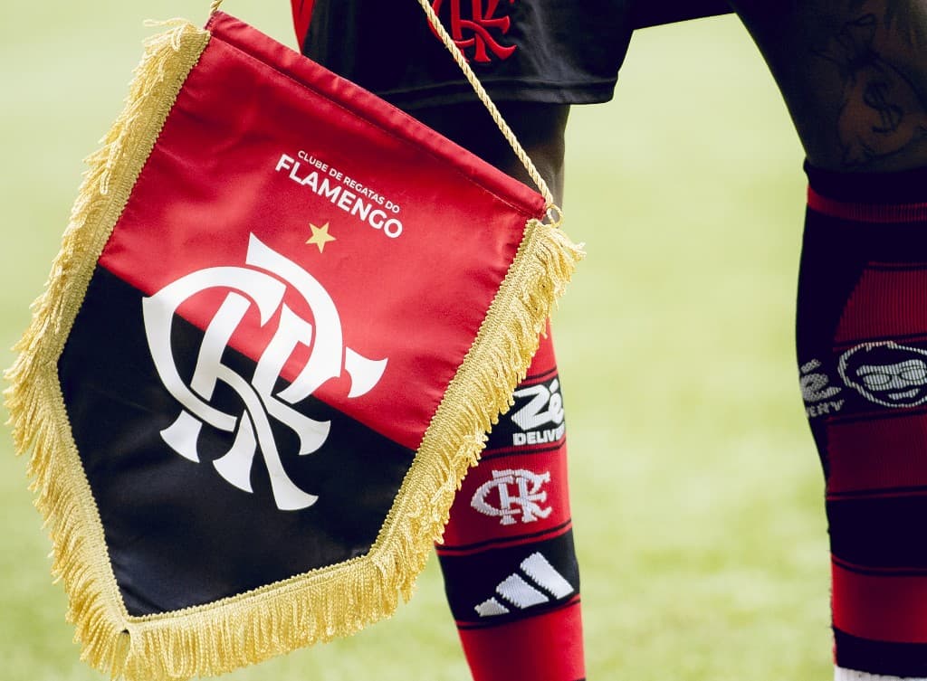 Bandeira do Flamengo em campo durante jogo, usada como símbolo na disputa entre clube, Libra e declarações de Leila Pereira