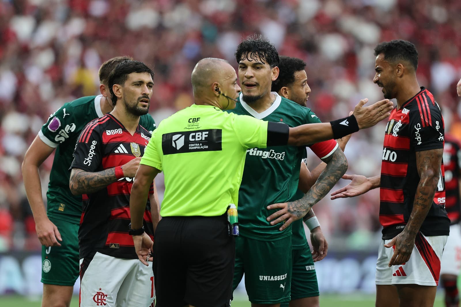 Gustavo Gómez, do Palmeiras, e Giorgian de Arrascaeta, do Flamengo, conversam com o árbitro Wilton Sampaio durante a partida entre Flamengo e Palmeiras pelo Brasileirão 2025, no Estádio do Maracanã, em 19 de outubro de 2025, no Rio de Janeiro, Brasil.