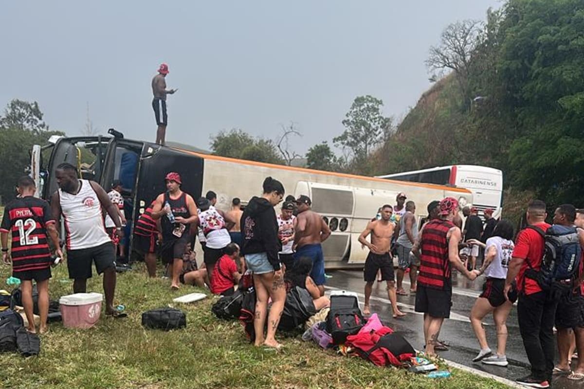 Cena mostra ônibus tombado e torcedores em volta na estrada entre Rio de Janeiro e São Paulo