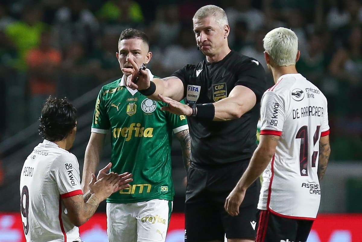 Anderson Daronco sinaliza marcação enquanto Pedro, no chão, aplaude e Arrascaeta só observa durante um Flamengo x Palmeiras