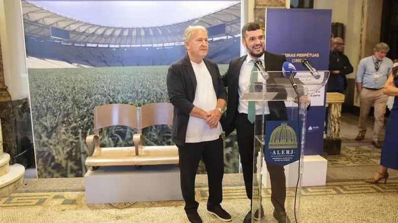 Zico em pé sendo homenageado por representante da Alerj em exposição dos 75 anos de Maracanã