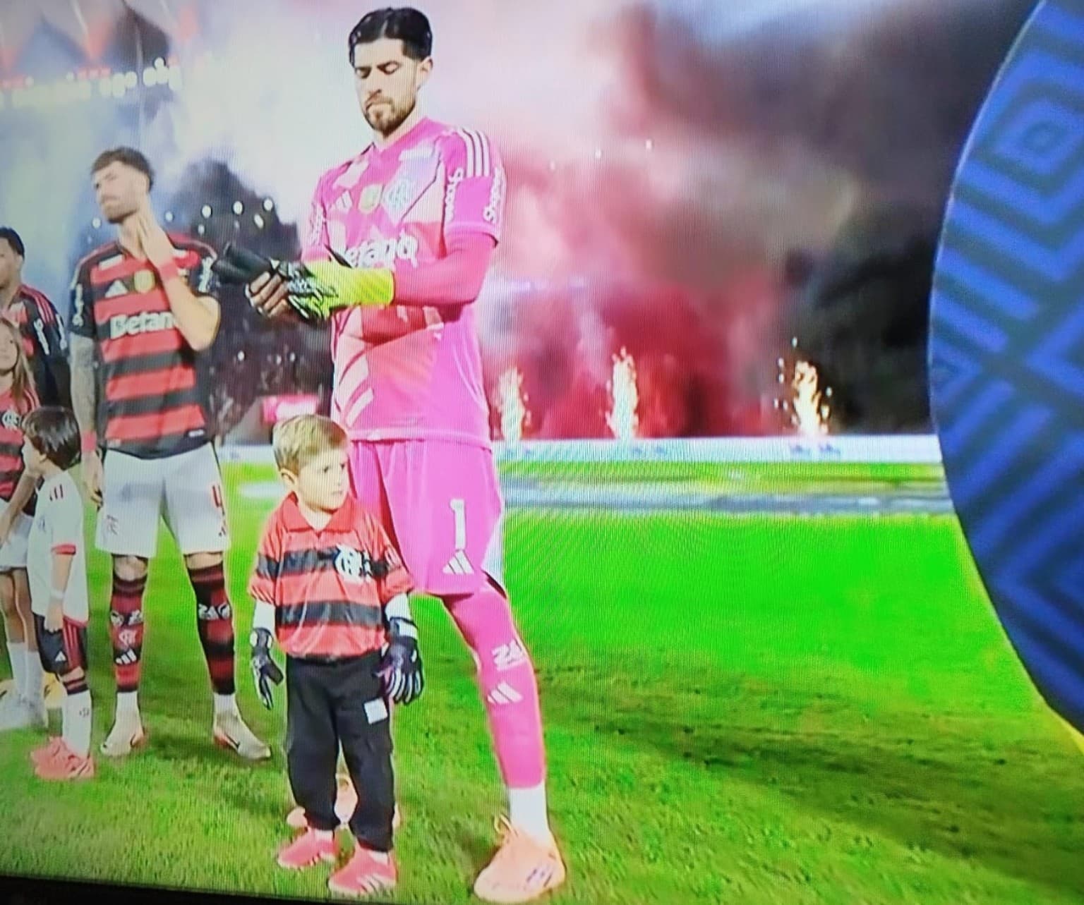 Agustín Rossi, goleiro do Flamengo, ao lado do filho vestido com camisa retrô rubro-negra e luvas de goleiro durante a entrada em campo no Maracanã, antes da partida contra o Sport em 2025.