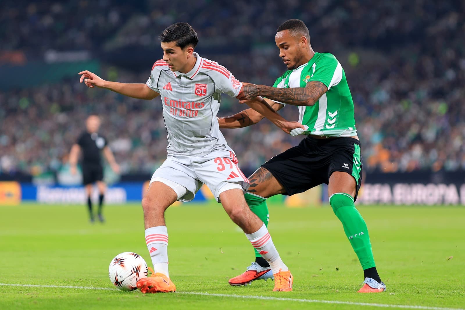 Mathys De Carvalho, do Olympique Lyonnais, é desafiado por Natan, do Real Betis, durante a partida da Fase MD4 da Liga Europa 2025/26 da UEFA entre Real Betis Balompie e Olympique Lyonnais, em La Cartuja de Sevilla, em 06 de novembro de 2025, em Sevilha,