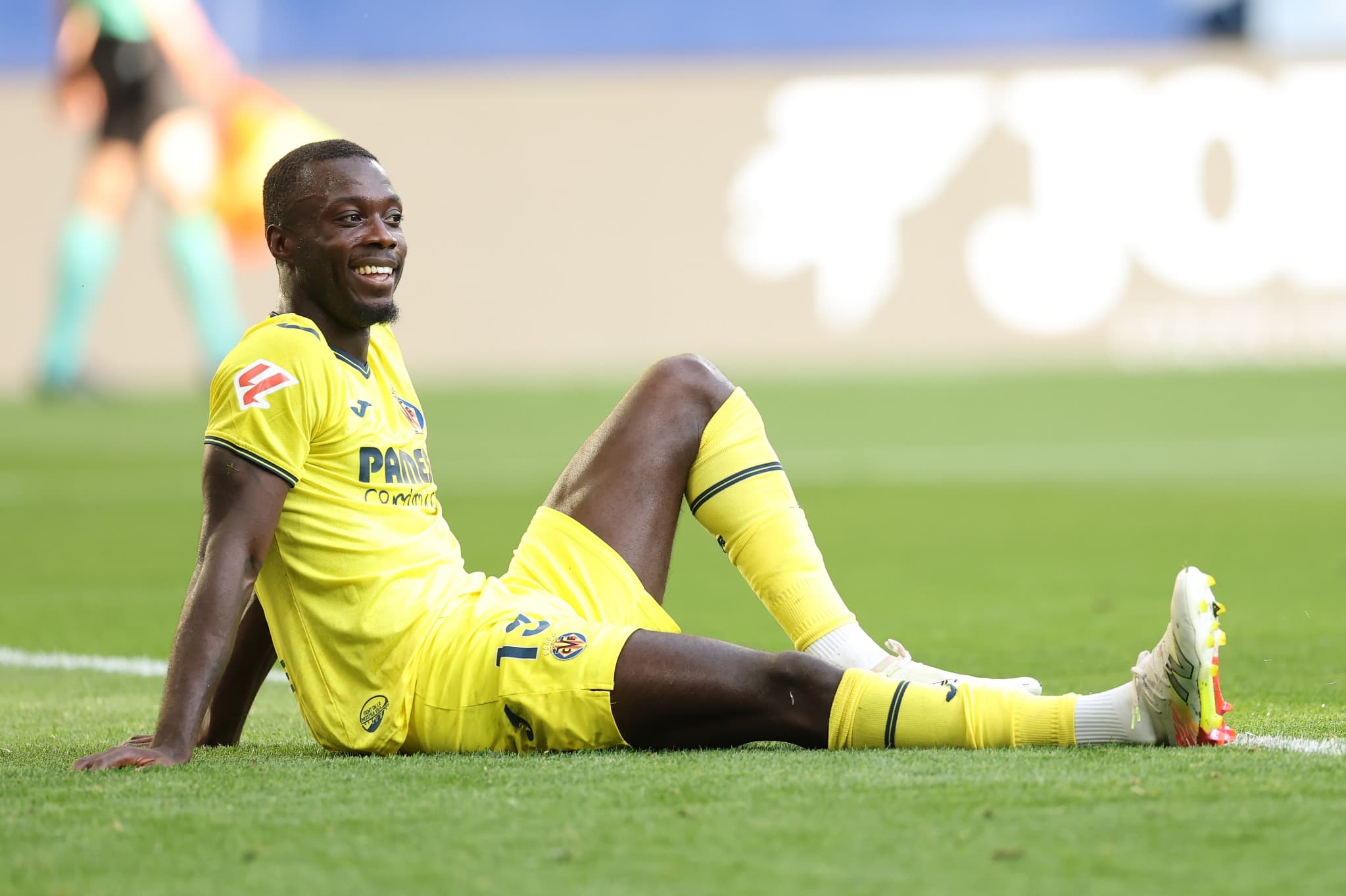 Jogador do Villarreal, Nicolas Pépé, sentado no gramado após disputa, vestindo uniforme amarelo, durante partida válida pela La Liga 2025, no Estádio de la Cerámica.