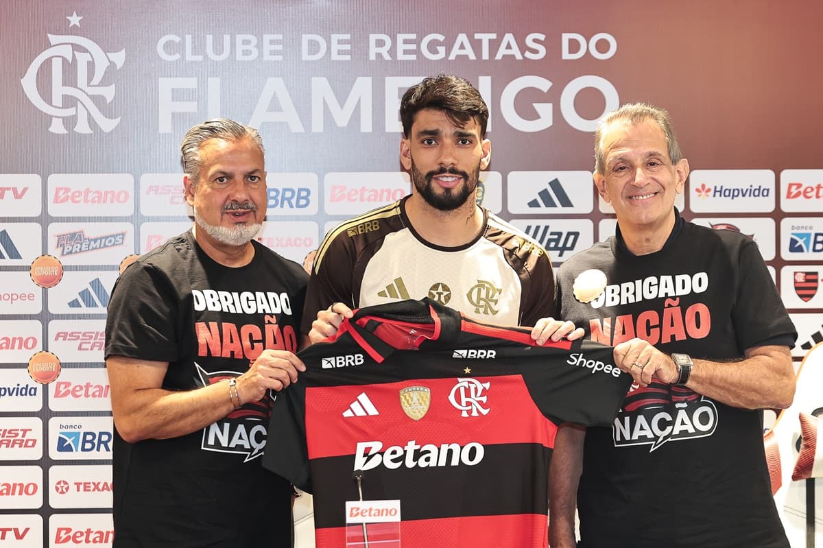 Lucas Paquetá posa ao lado de Boto e Bap enquanto segura camisa do Flamengo na apresentação oficial como jogador do clube