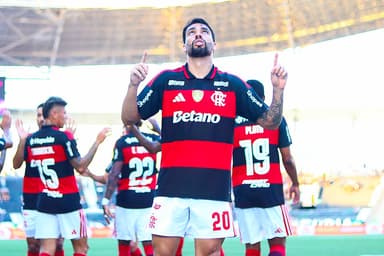Paquetá comemora gol apontando o dedo para o céu; ao fundo, jogadores se cumprimentam