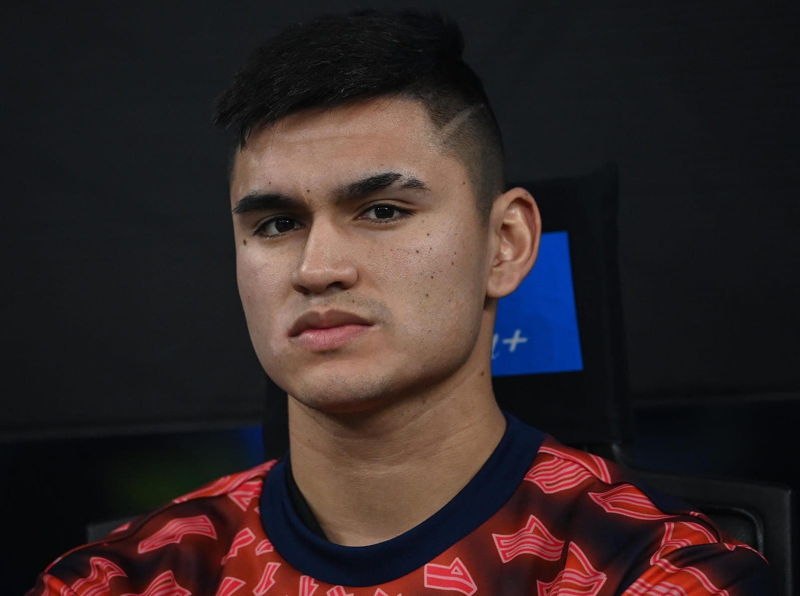 Carlos Alcaraz sentado no banco e olhando com expressão séria para câmera