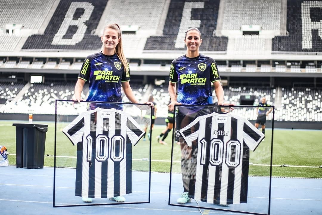 Jogadoras posam com placa comemorativa de 100 jogos!