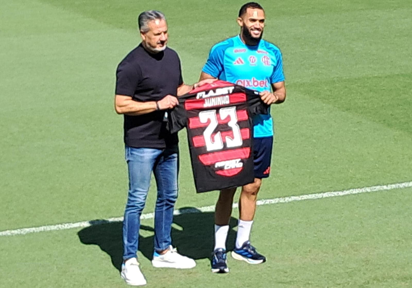 Juninho segura camisa do Flamengo com José Boto no Ninho do Urubu