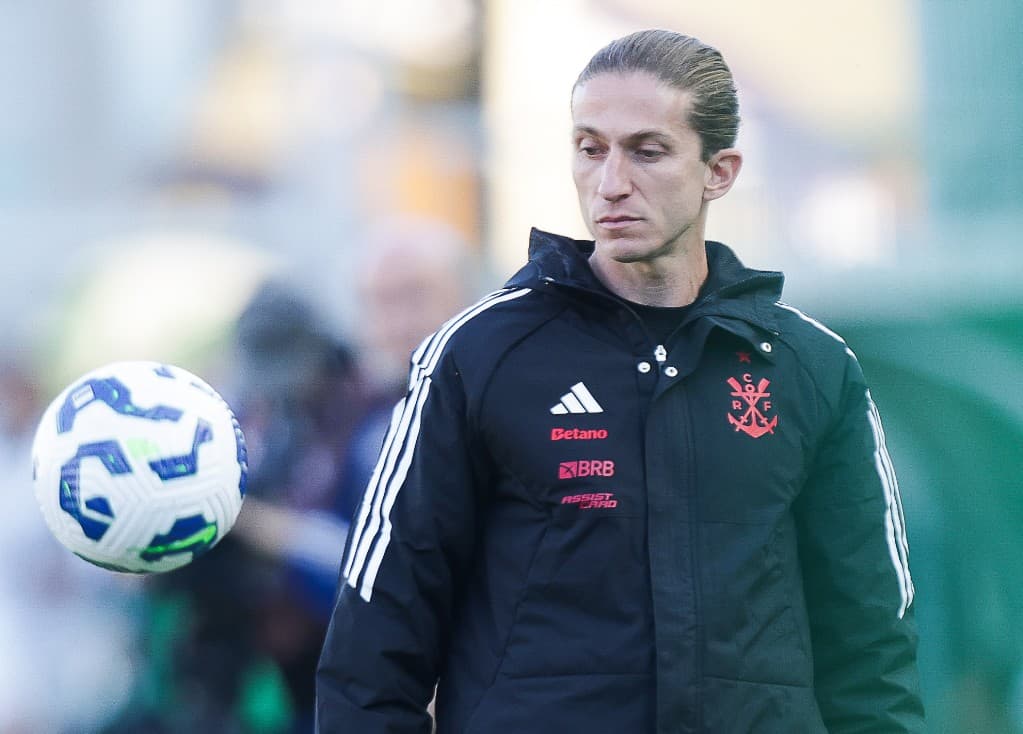 Filipe Luís, técnico do Flamengo, observa a bola durante aquecimento no gramado; foco e concentração.