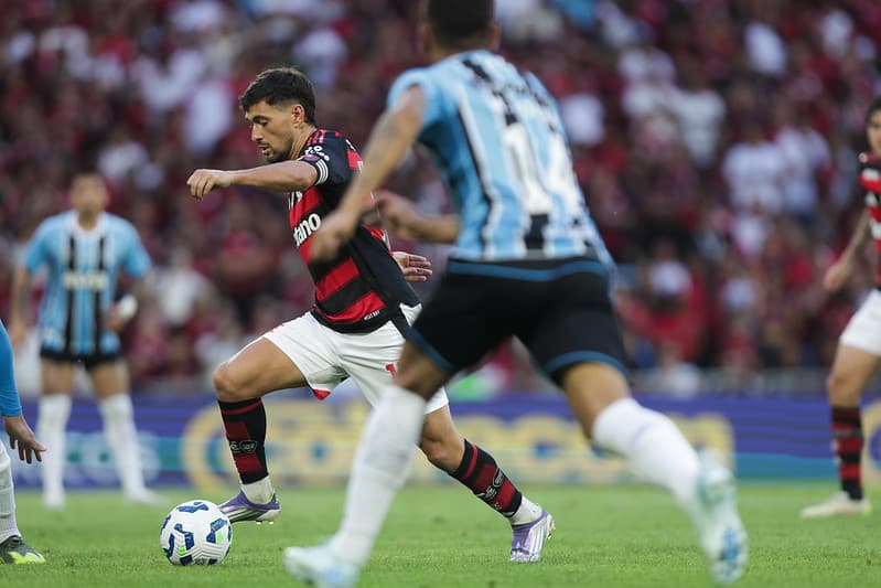 Arrascaeta conduz a bola marcado por jogadores do Grêmio durante Flamengo x Grêmio no Maracanã pelo Brasileirão 2025