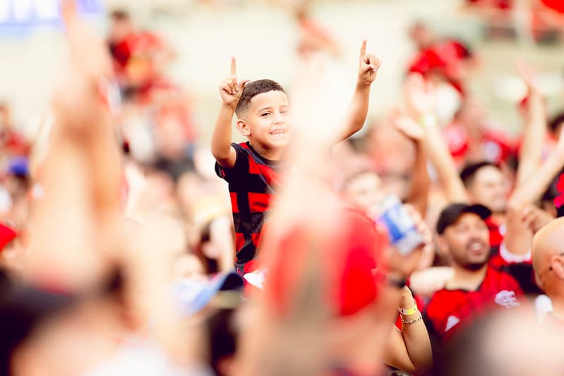 Criança rubro-negra comemora nas arquibancadas do Maracanã em jogo do Flamengo, simbolizando a torcida que busca ingressos para a Libertadores 2025