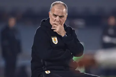 Marcelo Bielsa senta e leva as mãos à boca durante partida do Uruguai, após reclamar bastante com a equipe