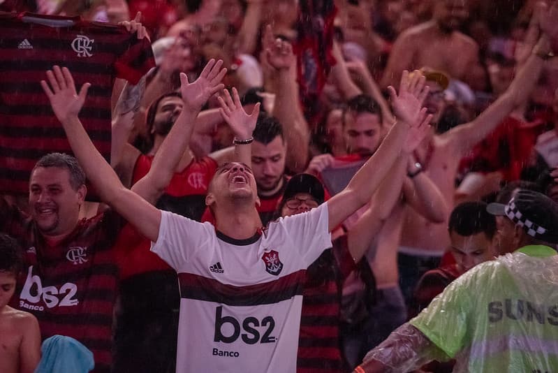 Torcedores do Flamengo presentes na Fan Fest do Maracanã levantam as mãos para o céu comemorando gol de Gabigol na final da Libertadores 2019