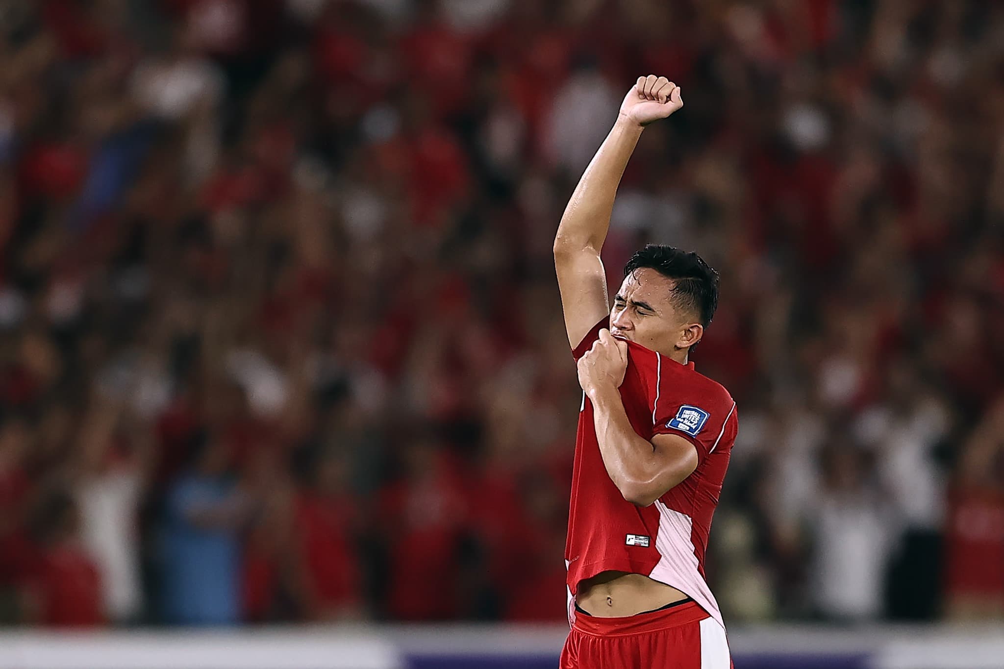Marselino Ferdinan, jogador da seleção da Indonésia, ergue o punho e beija o escudo após a vitória por 1 a 0 sobre o Bahrein nas Eliminatórias Asiáticas.