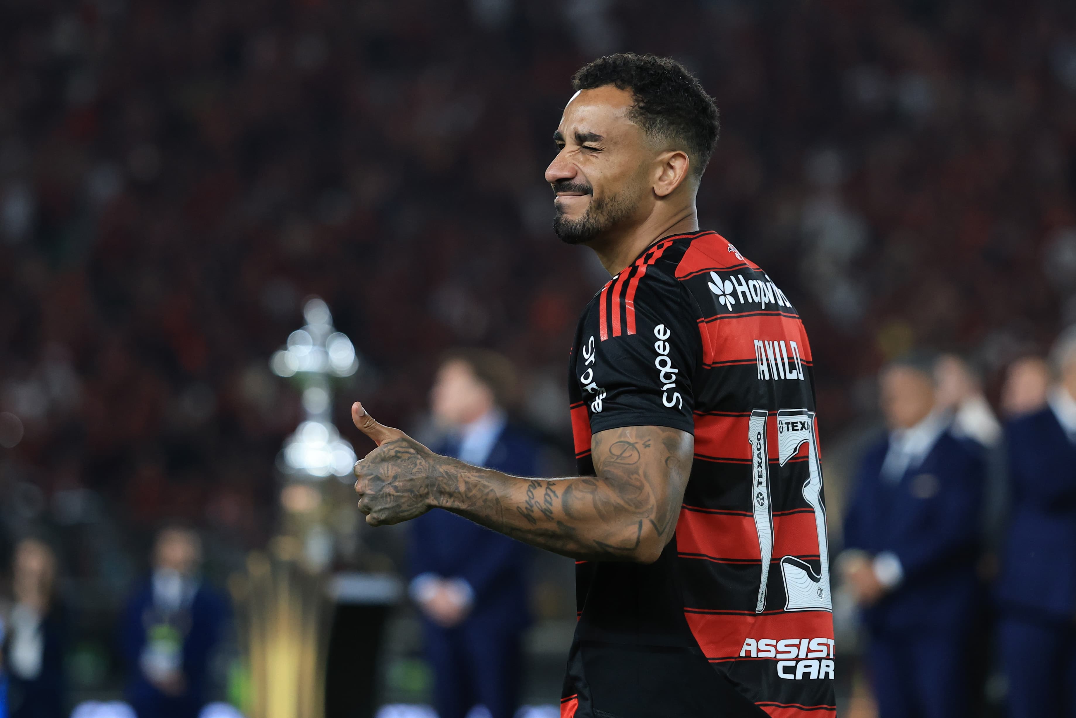 Danilo, autor do gol do titulo do Flamengo na Libertadores, rindo e fazendo sinal de positivo, com a taça de fundo