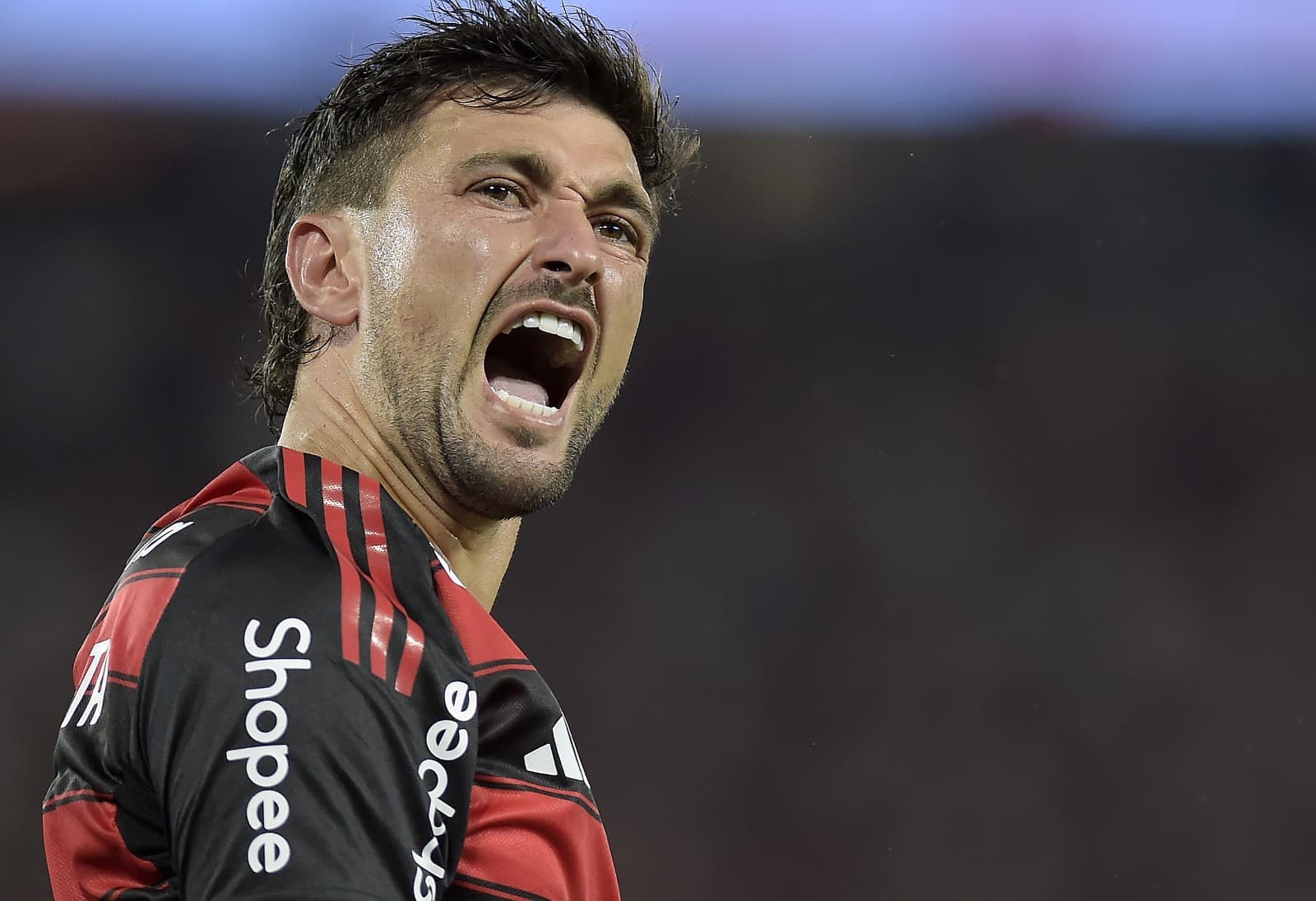 Arrascaeta grita ao comemorar gol do Flamengo sobre o Bragantino; Logo da Shopee na manga em destaque na foto