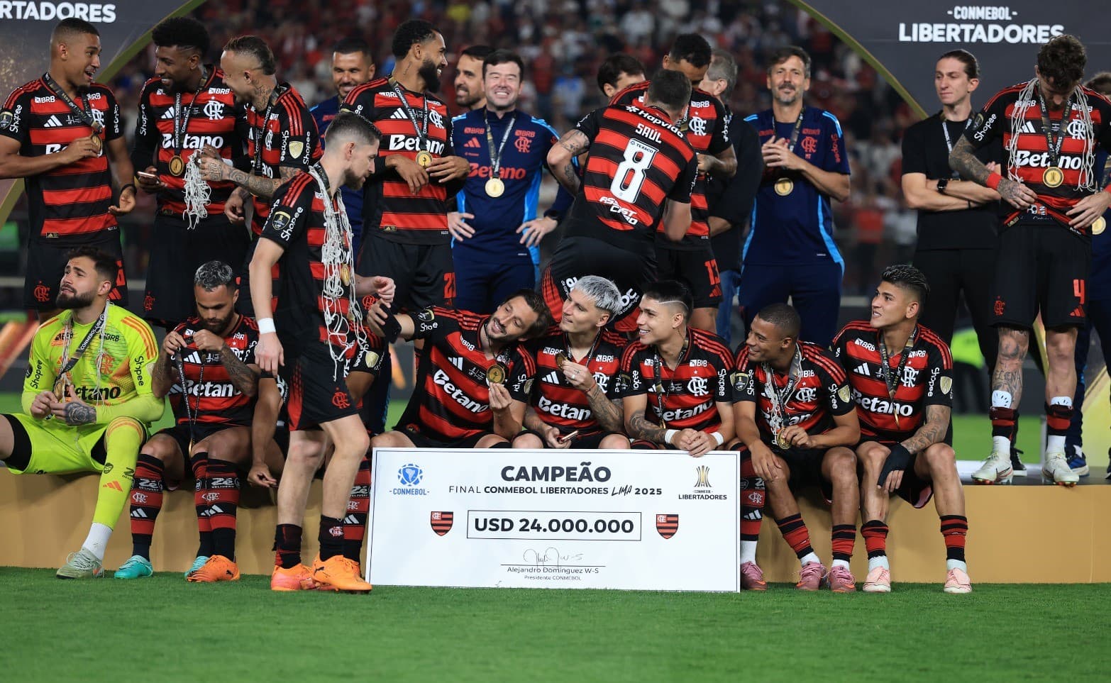 Jogadores do Flamengo, separados em diferentes grupos, tiram fotos com a medalha no palco da Libertadores